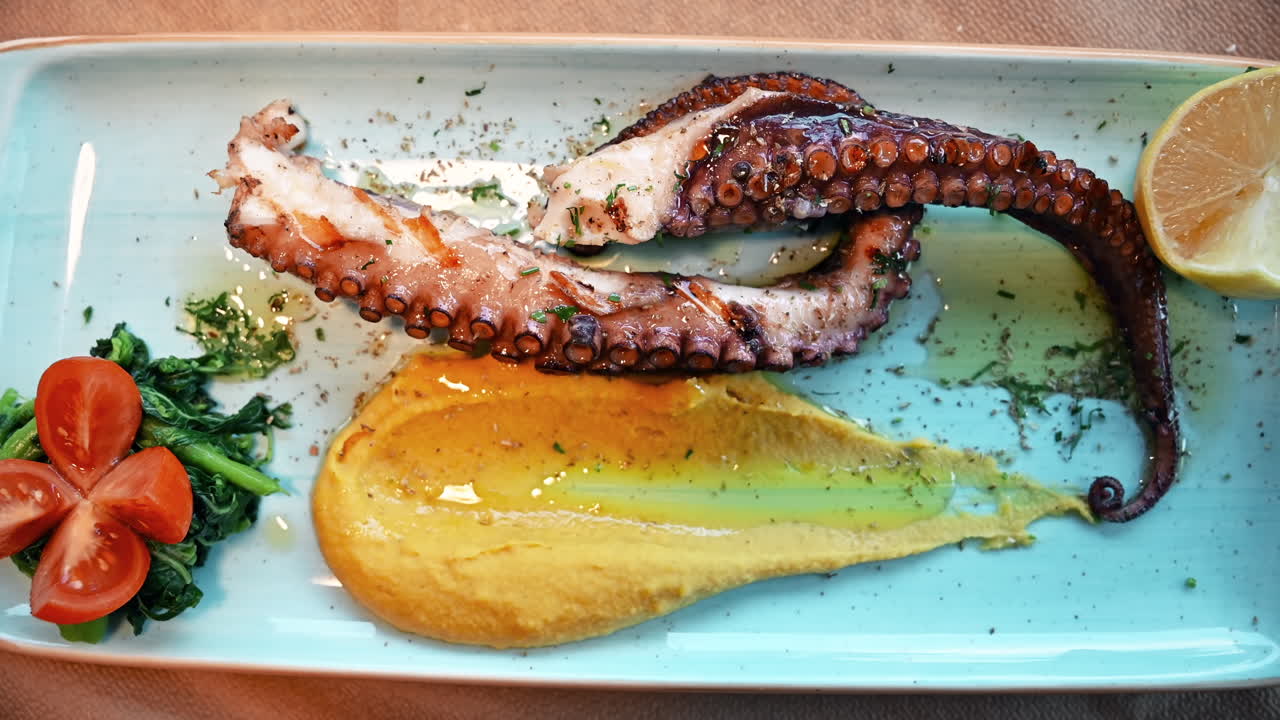 Polpo cotto su un piatto con condimenti e verdure in Grecia