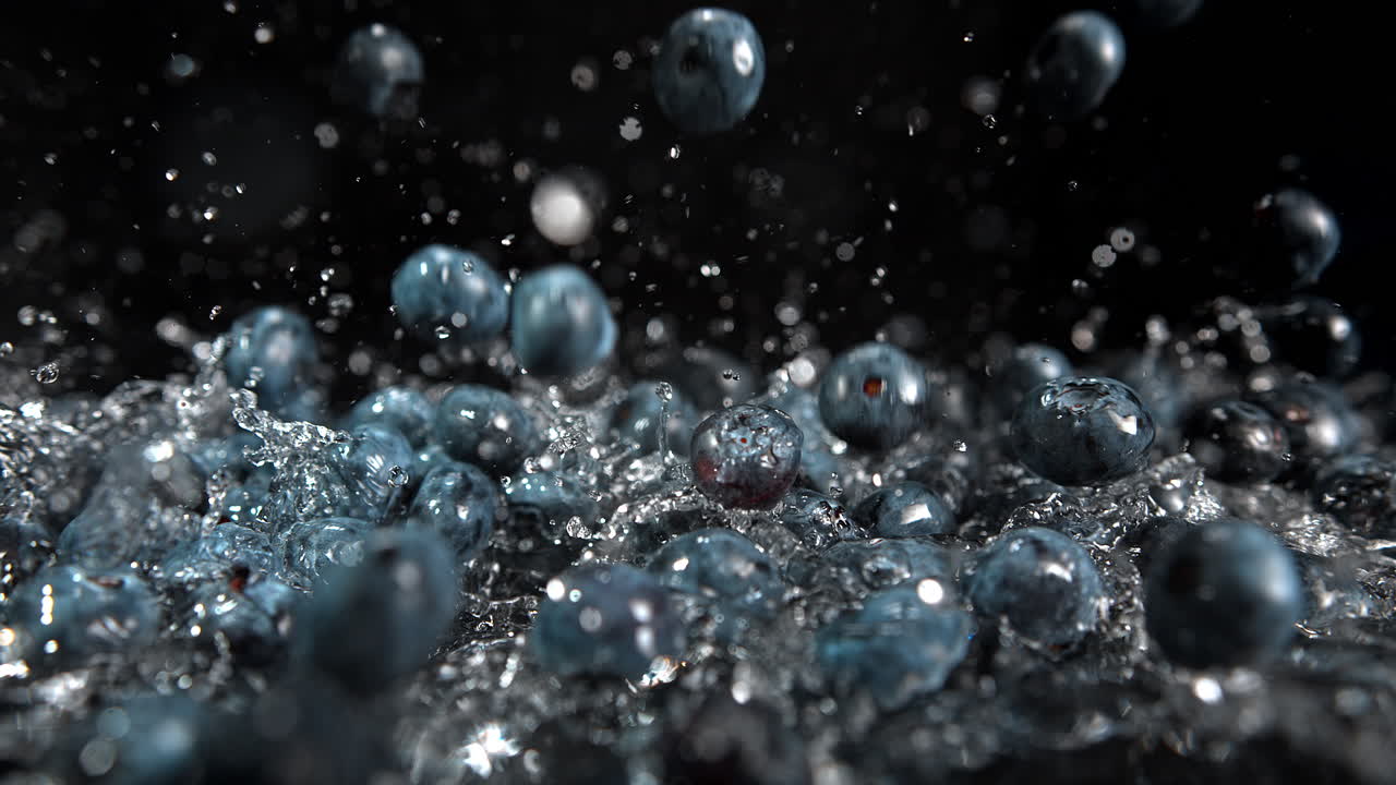 블루베리는 은 표면에 떨어지고, 물방울이 느린 동작과 매크로로 어집니다.