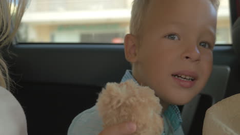 boy with plush toy on the car back seat