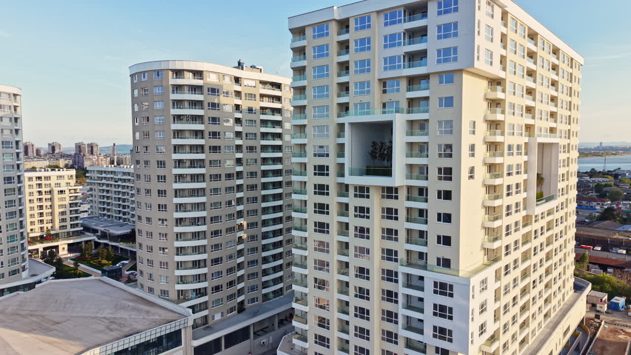 Edifícios altos em uma área urbana moderna com céu azul claro ao fundo, mostrando uma cena de cidade vibrante.