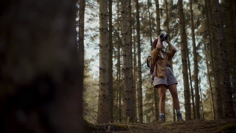 woman with backpack searching through binoculars