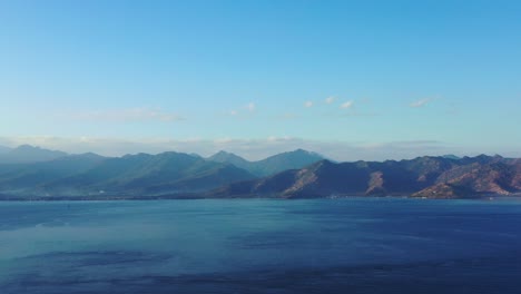 peaceful beautiful blues of wide sea and high mountains of volcanic islands under foggy sky of morning, indonesia