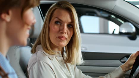 two women discussing a car in a showroom