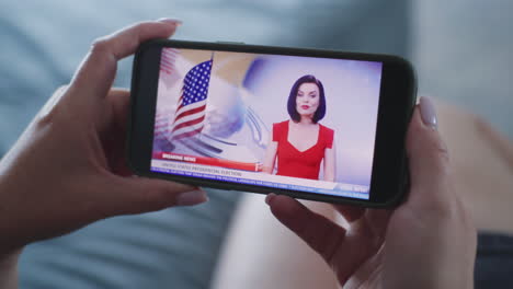 woman watching news report on election on mobile phone