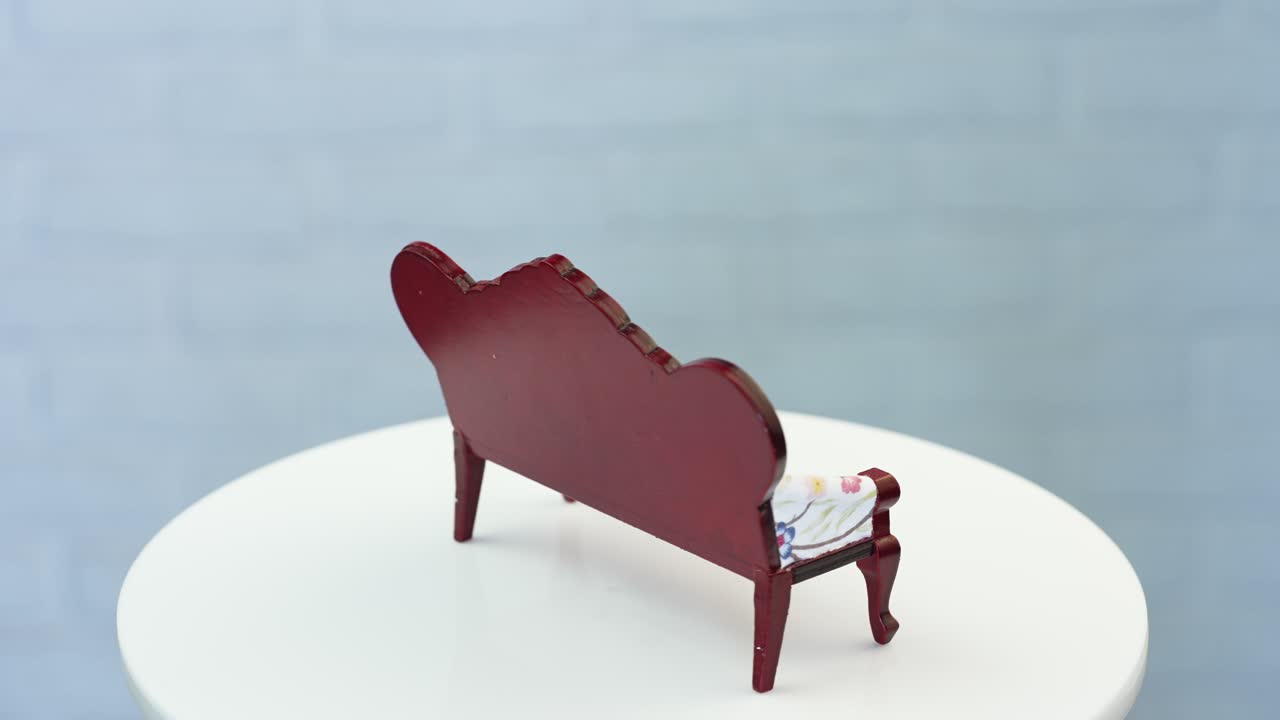 Amazing old-fashioned sofa for doll's house furnishing. Adorable piece of miniature furniture at the rotating table. Close up.