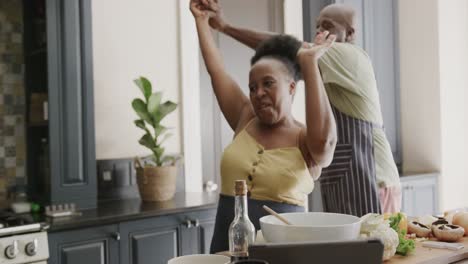 Happy-senior-african-american-couple-dancing-in-ktichen-in-slow-motion