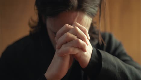 Young-man-in-old-church-building-in-front-of-stained-glass-window-kneeling,-praying,-worshipping