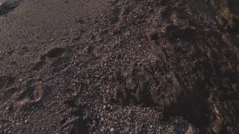 aerial close-up shot of rocky charcon beach washed by calm sea waters, spain