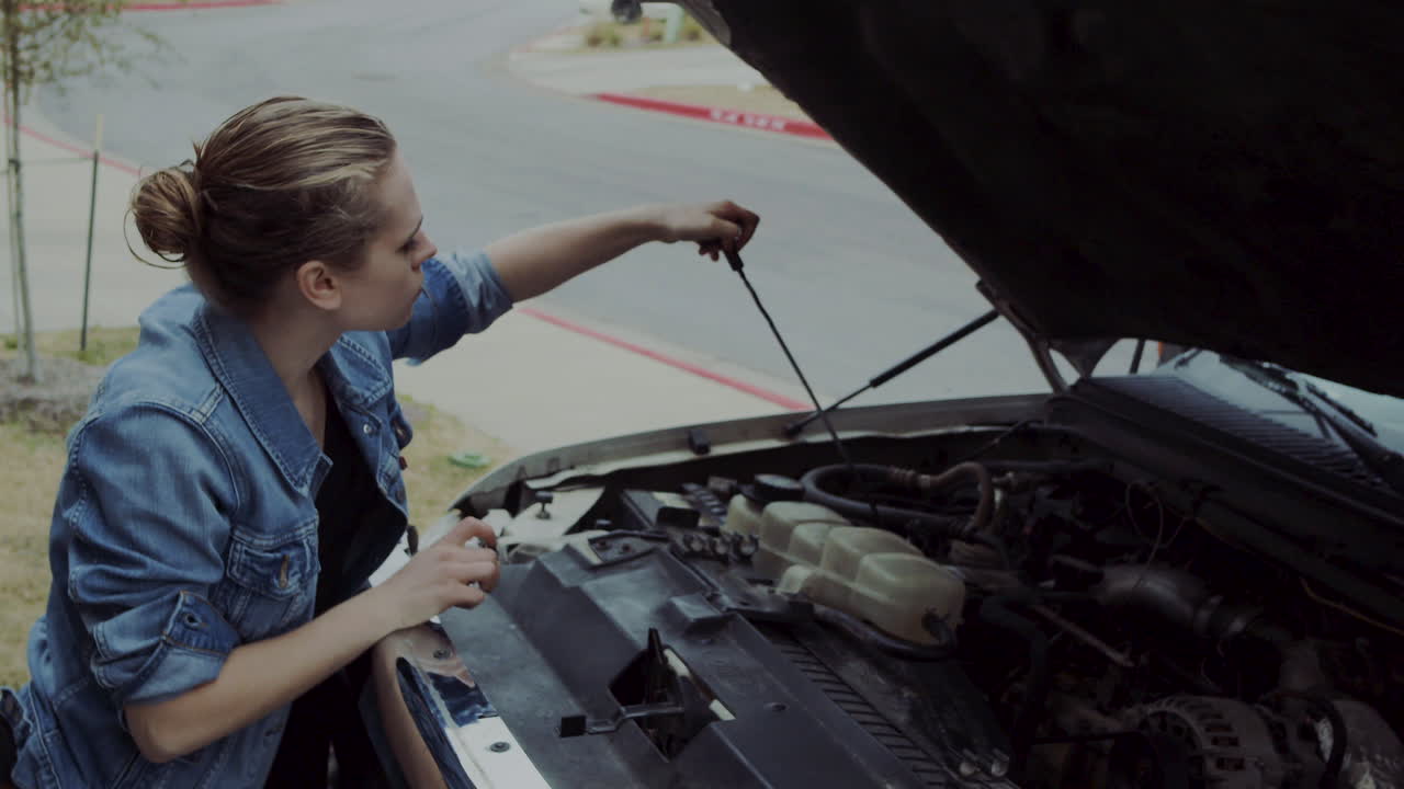 Woman in early 20s checking under the hood of a truck and going under the truck to find and fix mechanical problem. 60 fps 4k