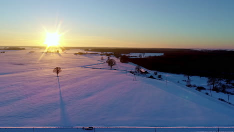 Un-Paisaje-Soleado-Y-Nevado-Durante-Un-Amanecer-Dorado-Y-Largas-Sombras-De-Los-árboles-Del-Campo---Sobrevuelo-Aéreo-Deslizante