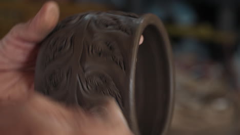 close-up of a potter shaping and decorating a clay bowl