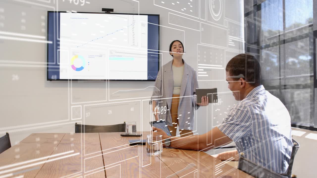 Seated colleague tapping tablet, business presenter stepping forward highlighting charts with HUD