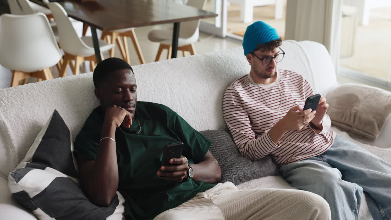 Two men relaxing on a couch using mobile phones