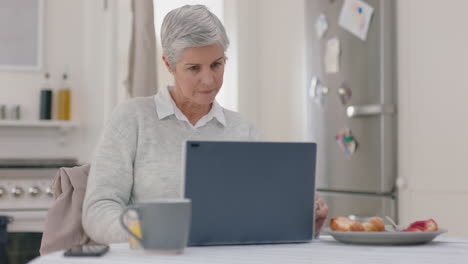 Mujer-Madura-Feliz-Usando-Una-Computadora-Portátil-En-Casa-Escribiendo-Mensajes-Navegando-En-Línea-Disfrutando-Trabajando-En-La-Mañana-En-El-Desayuno-Imágenes-De-4k