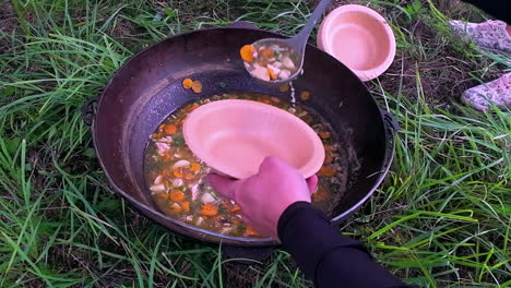 closeup of vegetable soup being served in outdoor nature garden setup