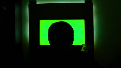 rear view of man looking at green tv. concept. man was watching green-screen tv sitting in dark. man turned off tv and went to sleep