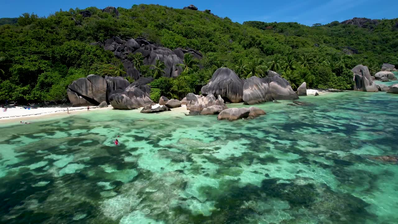 Veduta aerea della spiaggia di Anse Source D'argent alle Seychelles con massi iconici e una donna in kayak.