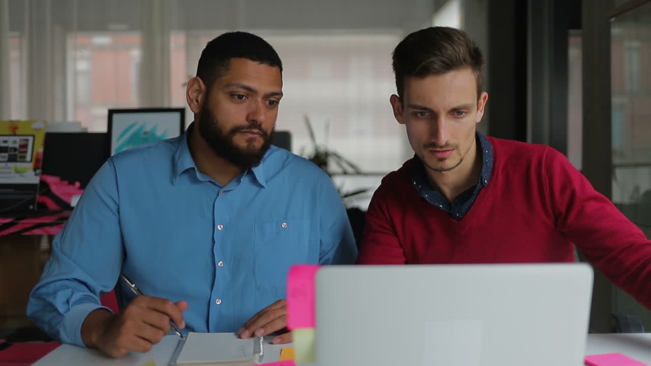 Thoughtful bearded men sitting at table with laptop.