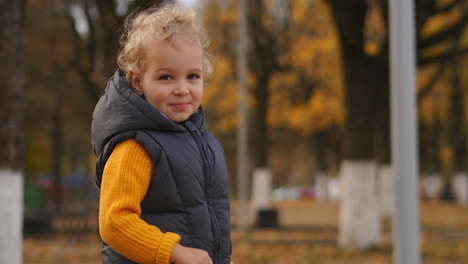 Süßes-Kleines-Kind-Mit-Blonden-Lockigen-Haaren-Im-Herbst-Parkbereich-Mittleres-Porträt-Eines-Lustigen-Lächelnden-Jungen-Glückliche-Kindheit