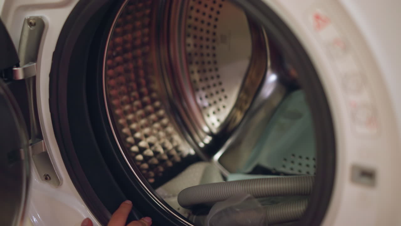 A modern washing machine interior with visible parts and equipment, the interior of the machine is being inspected, revealing its drum and internal components in a brightly lit store