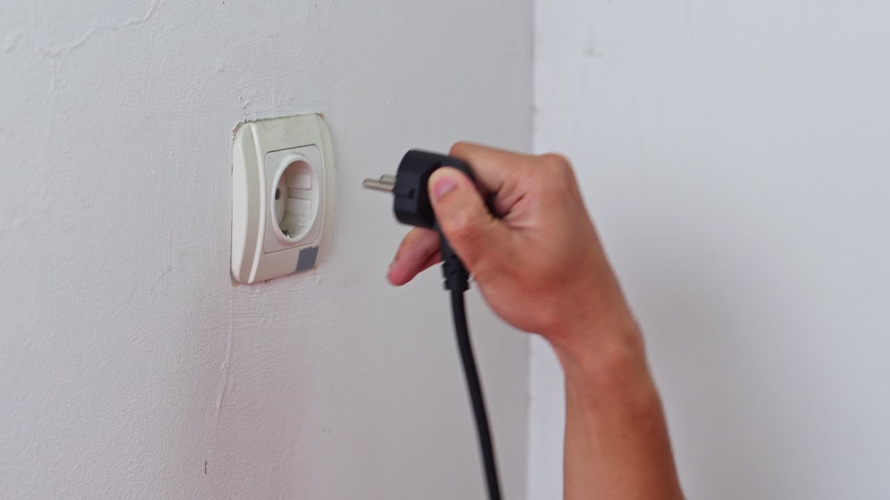 Action shot of disconnecting power plug from an outlet to reduce energy consumption