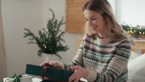 caucasian woman opening christmas presents with white jumper and being surprised