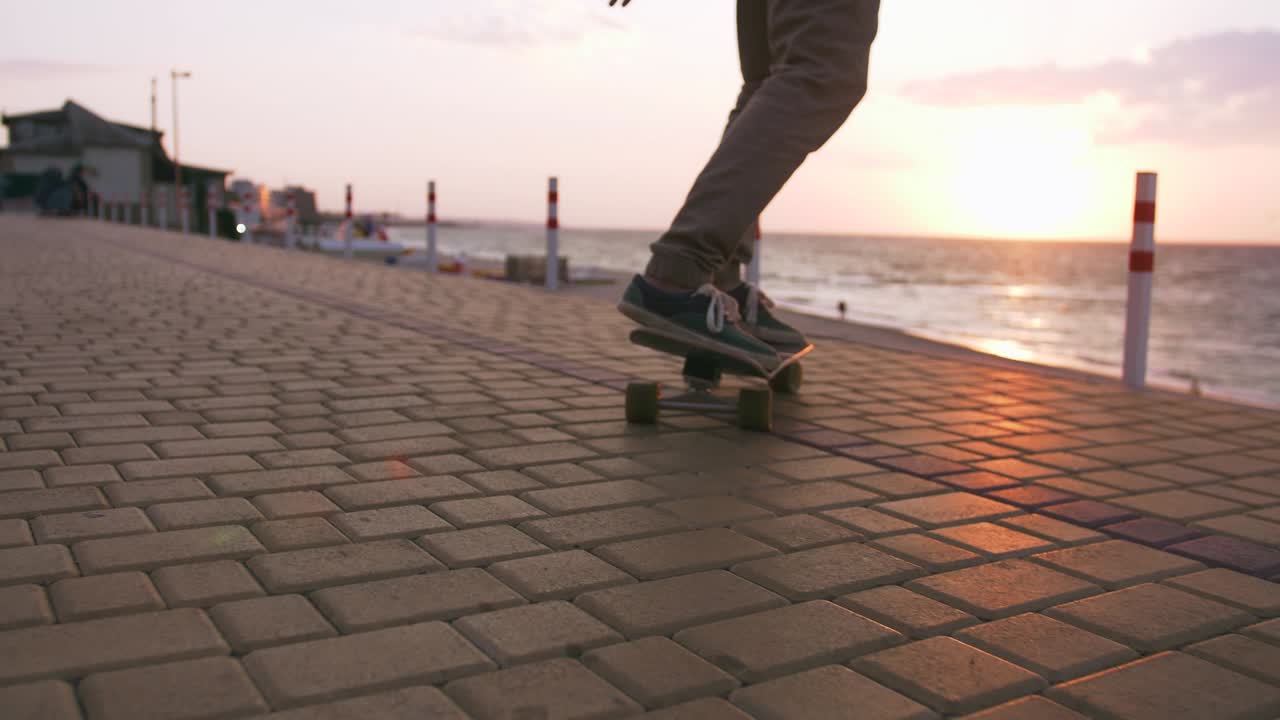 Close up shot of young man skateboarding on the road near the sea, slow motion