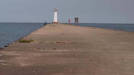 Toma-Panorámica-De-Los-Faros-Y-El-Barco-En-Sodus-Point,-Un-Lugar-De-Vacaciones-En-Nueva-York-En-La-Punta-De-La-Tierra-A-Orillas-Del-Lago-Ontario.