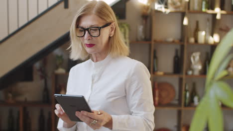 senior woman working on tablet in restaurant