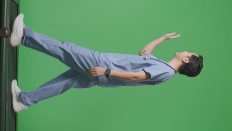 full body of side view asian male doctor with stethoscope waving hand and smiling while walking on green screen background in the hospital