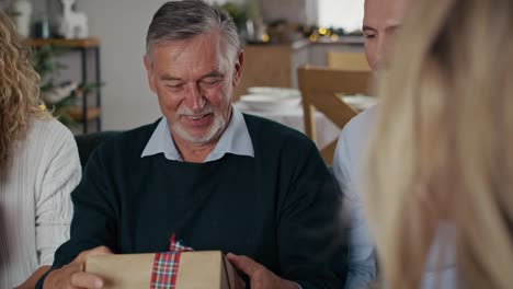 Frau-überreicht-Dem-älteren-Vater-Im-Urlaub-Das-Weihnachtsgeschenk.