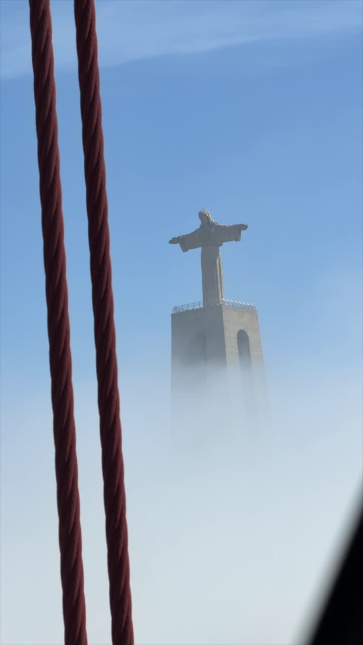 Statua del Cristo Re che emerge dalla nebbia a Lisbona.