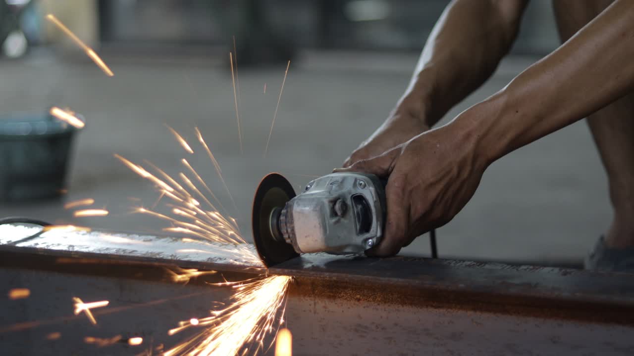 노동자 들 은 수동 가루 를 사용 하여 철 을 자르고 있다. 가루 에서 어지는 불꽃 이 곳곳 에 어지고 있다