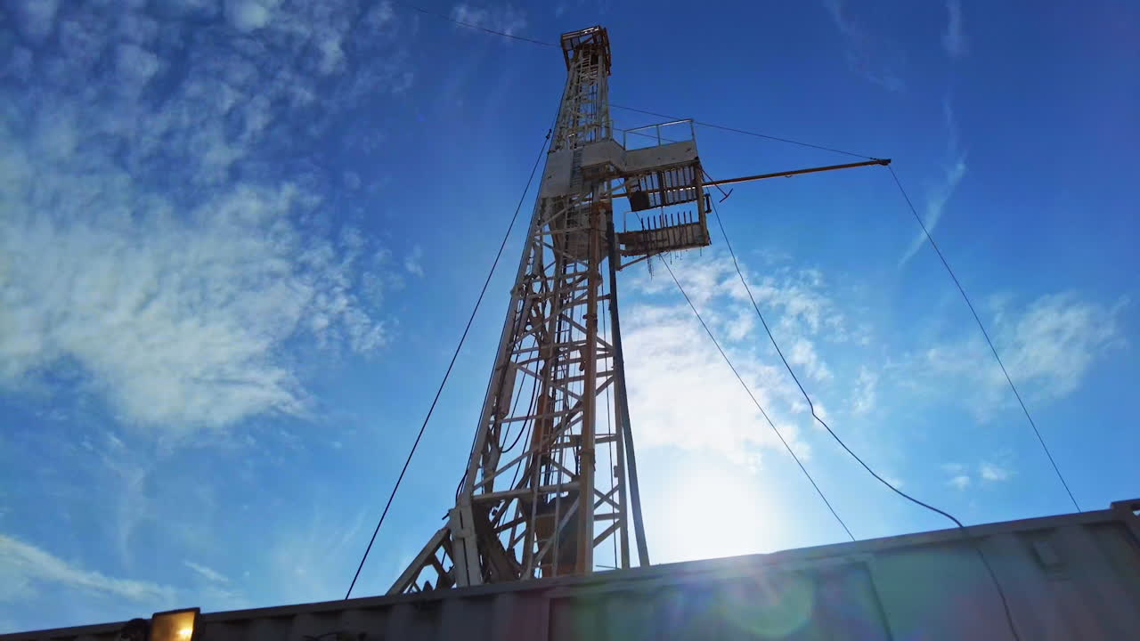 Derrick at the site for drilling natural resources. Low angle view at the tower for oil production at the backdrop of blue sky.
