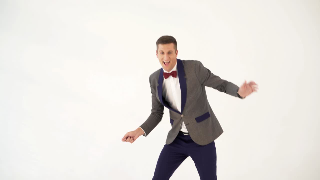 fun showman in trendy costume is parodying a man playing table tennis on a white background in the studio