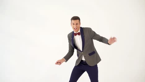 fun showman in trendy costume is parodying a man playing table tennis on a white background in the studio