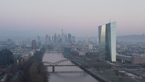 Frankfurter-Skyline-Mit-EZB-Turm-Im-Vordergrund-In-Der-Abenddämmerung-An-Einem-Nebligen-Morgen