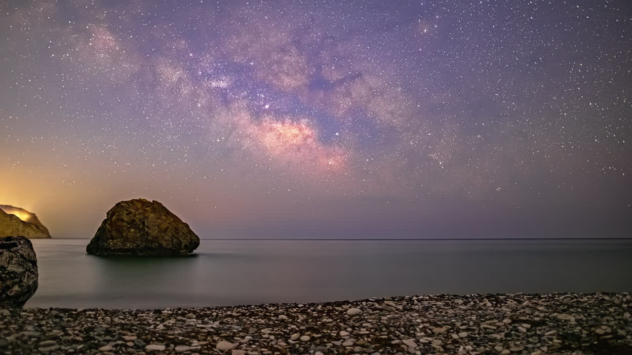 Pebbles on the beach at Aphrodite's Rock, Cyprus with a Milky Way time lapse
