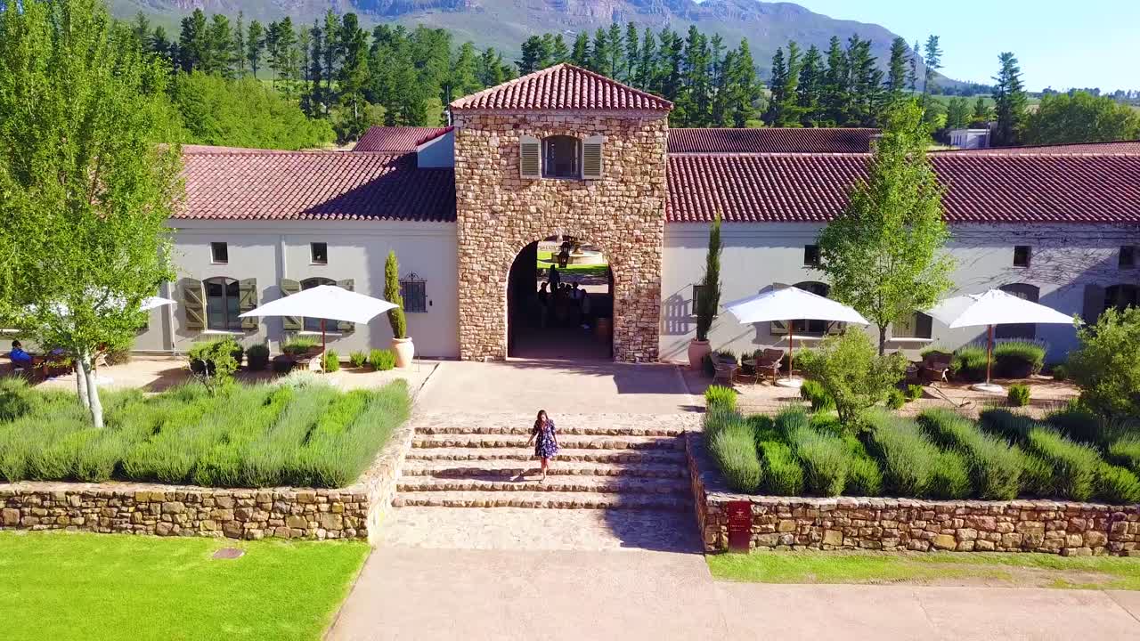 Ripresa aerea inversa di una donna che si allontana da una cantina a Stellenbosch, Città del Capo, Sudafrica.