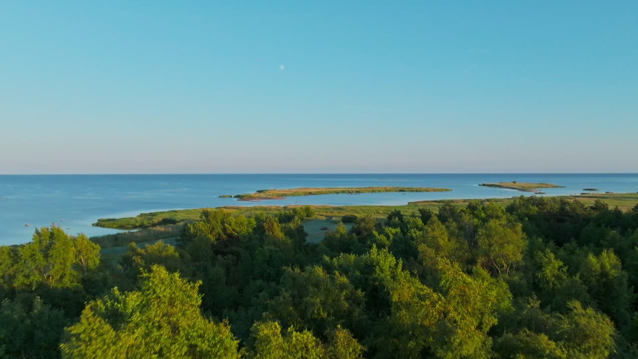 Movement over trees towards two islets near the coast at a summer sunset