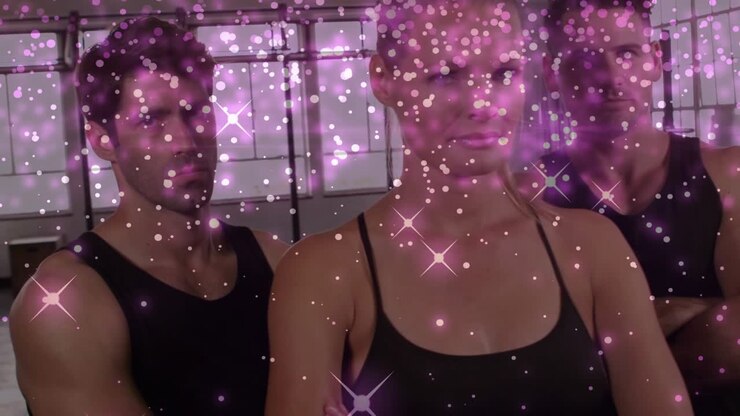 Donna al centro che guida due uomini che posano in studio, effetto glitter che determina sottili cambiamenti per una pubblicità di fitness