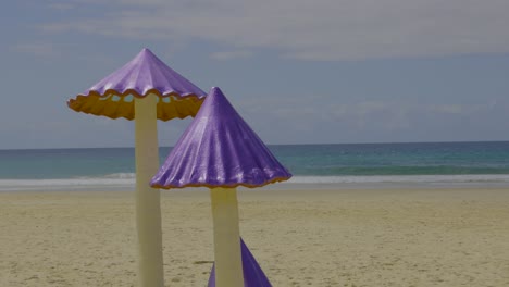 purple mushroom sculptures on sandy beach