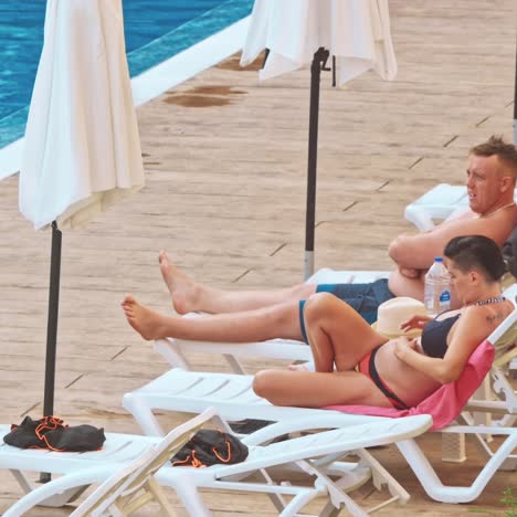 people sitting by the poolside of a resort swimming pool during summer holiday