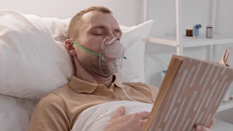 man reading in hospital bed