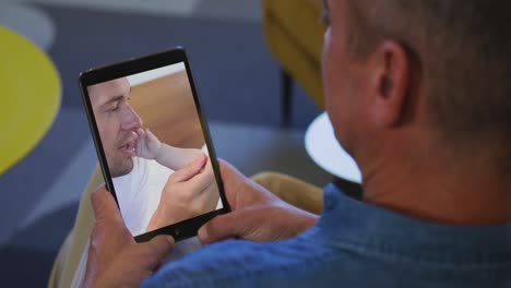 Älterer-Mann,-Der-Zu-Hause-Einen-Video-Chat-Auf-Seinem-Digitalen-Tablet-Führt