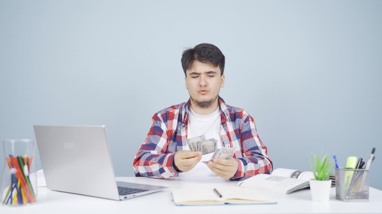 노트북을 보고 돈을 세는 남자.
