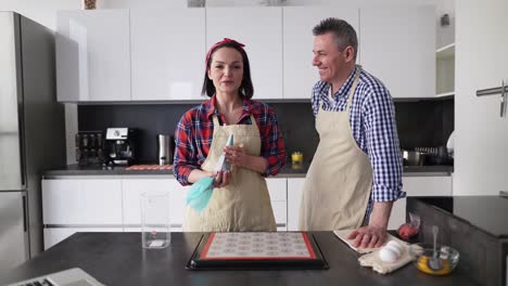 Pareja-Positiva-En-La-Cocina-Haciendo-Macarrones-En-Casa,-Hablando-En-Cámara