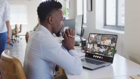 African-american-man-using-laptop-for-video-call,-with-diverse-business-colleagues-on-screen