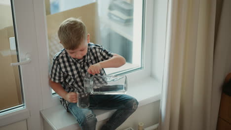 boy pouring water from a jug into a glass