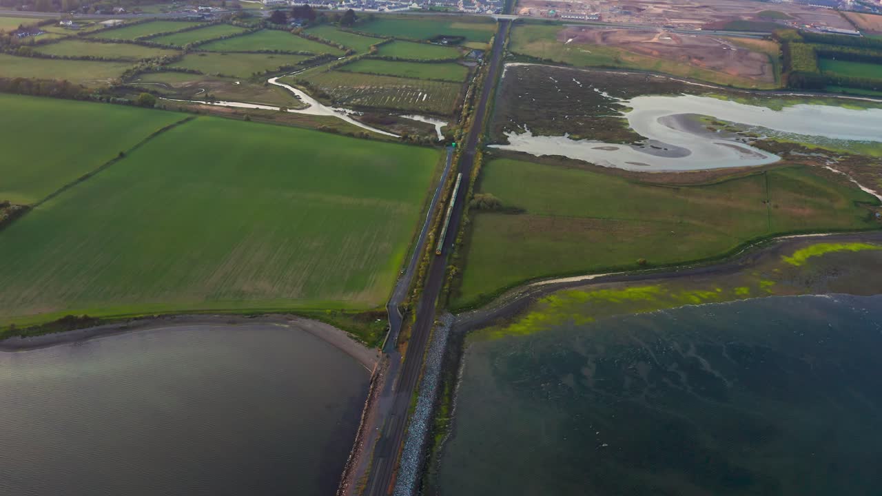 Aerial Orbit of Irish Dart Train Crossing Broadmeadow Viaduct Toward Donabate During Evening Light
